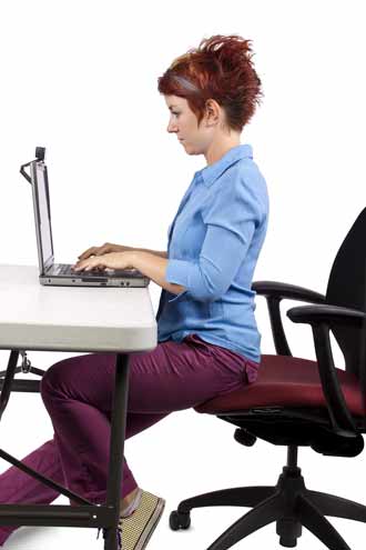 woman demonstrates the correct sitting position when sitting at a dektop computer